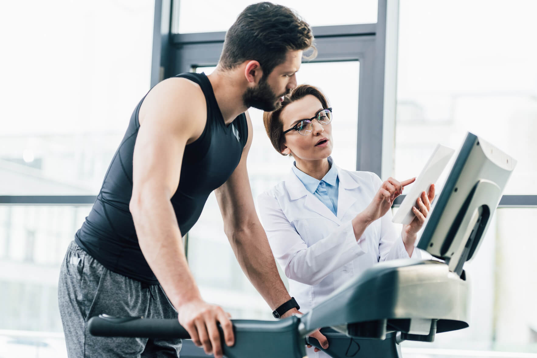 doctor showing person on treadmill information on screen